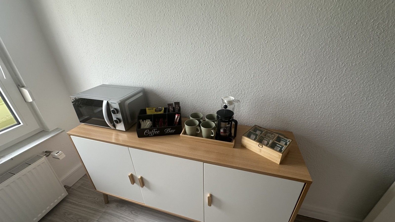 Eine Küchenzeile mit Mikrowelle, Kaffeemaschine und Aufbewahrungsboxen.