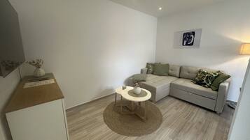 A modern living room with a sofa, a small round table, and a lamp.
