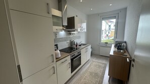 Una cocina moderna con armarios blancos, horno empotrado, microondas y ventana con vistas al exterior.