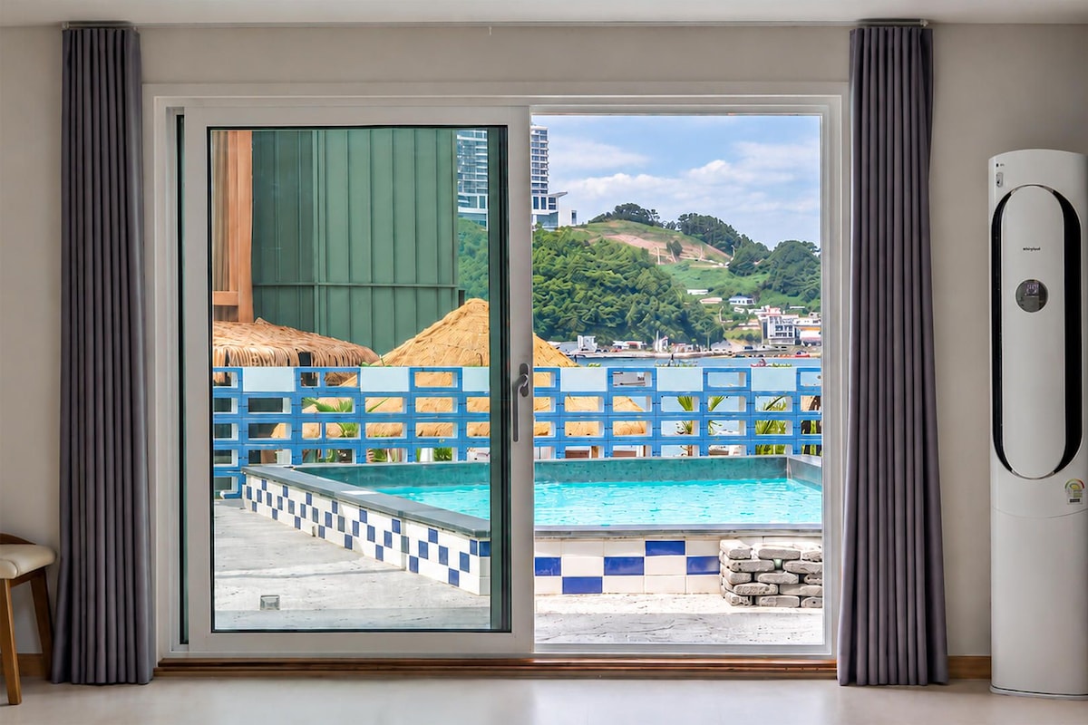 Une chambre avec vue sur une piscine, une porte-fenêtre coulissante et un climatiseur blanc.