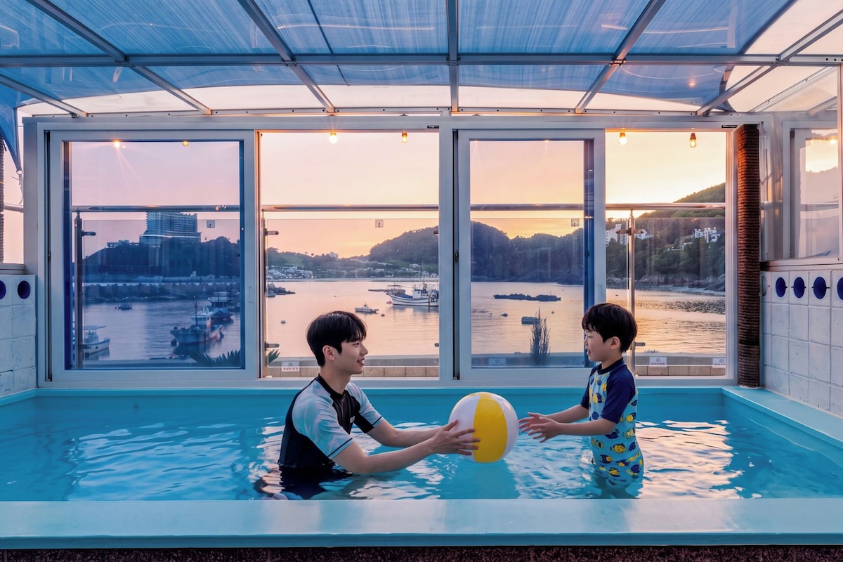 Une piscine intérieure avec vue sur un plan d’eau et sur le paysage urbain.