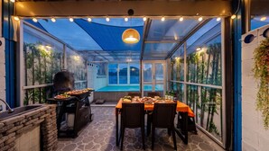 Une terrasse extérieure équipée d’un barbecue, d’une table à manger, de chaises et offrant une vue sur une piscine.