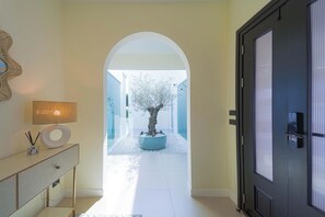 A hallway with a white floor, a black door, and a potted tree. - 3BR Luxury Pool Villa, Hua Hin (TP3) (Hua Hin)