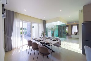 A modern dining area with a glass partition, a dining table set for six, and a view of the outdoors. - 3BR Luxury Pool Villa, Hua Hin (TP3) (Hua Hin)