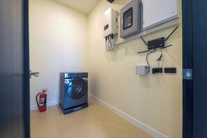 A laundry room with a washing machine, a fire extinguisher, and electrical outlets on the wall. - 3BR Luxury Pool Villa, Hua Hin (TP3) (Hua Hin)