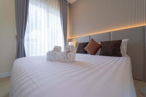 A hotel room with a large bed, a headboard with vertical lines, and a window with curtains. - 3BR Luxury Pool Villa, Hua Hin (TP3) (Hua Hin)