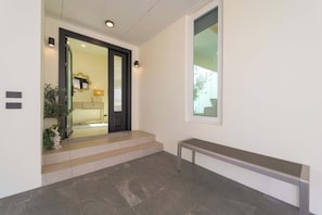 A clean, modern hallway with a bench, a door leading to a room, and a window with a view. - 3BR Luxury Pool Villa, Hua Hin (TP3) (Hua Hin)