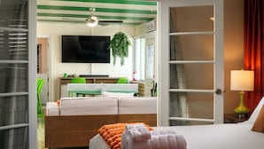 Een hotelkamer met een bed, een televisie, een bureau met stoel, een plant en een raam.