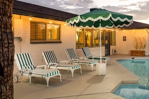A poolside area with lounge chairs and a covered umbrella.