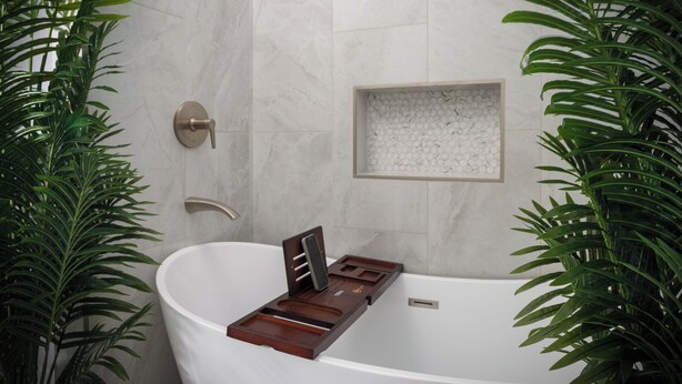 Een moderne badkamer met een vrijstaand bad, een wandmengkraan en een inbouwplank met decoratieve objecten.