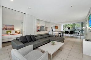 Ein modernes Wohnzimmer mit einem grauen Sofa, einem weißen Couchtisch und einem Essbereich mit Tisch und Stühlen.