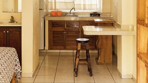 Cocina compacta con una isla central, una ventana con cortinas y armarios de madera.