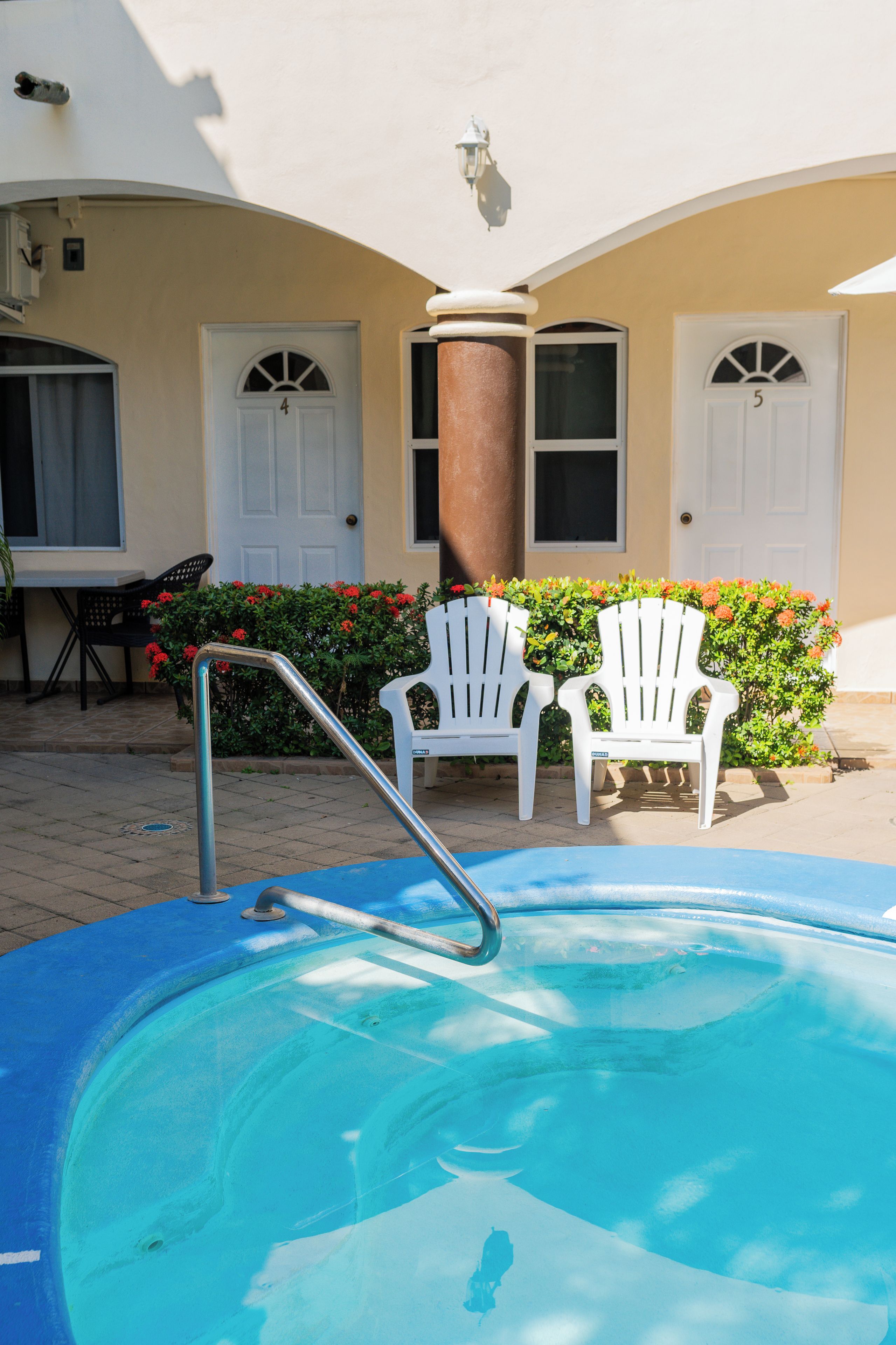 A swimming pool with a ladder, two white chairs, and a door with the number 4.