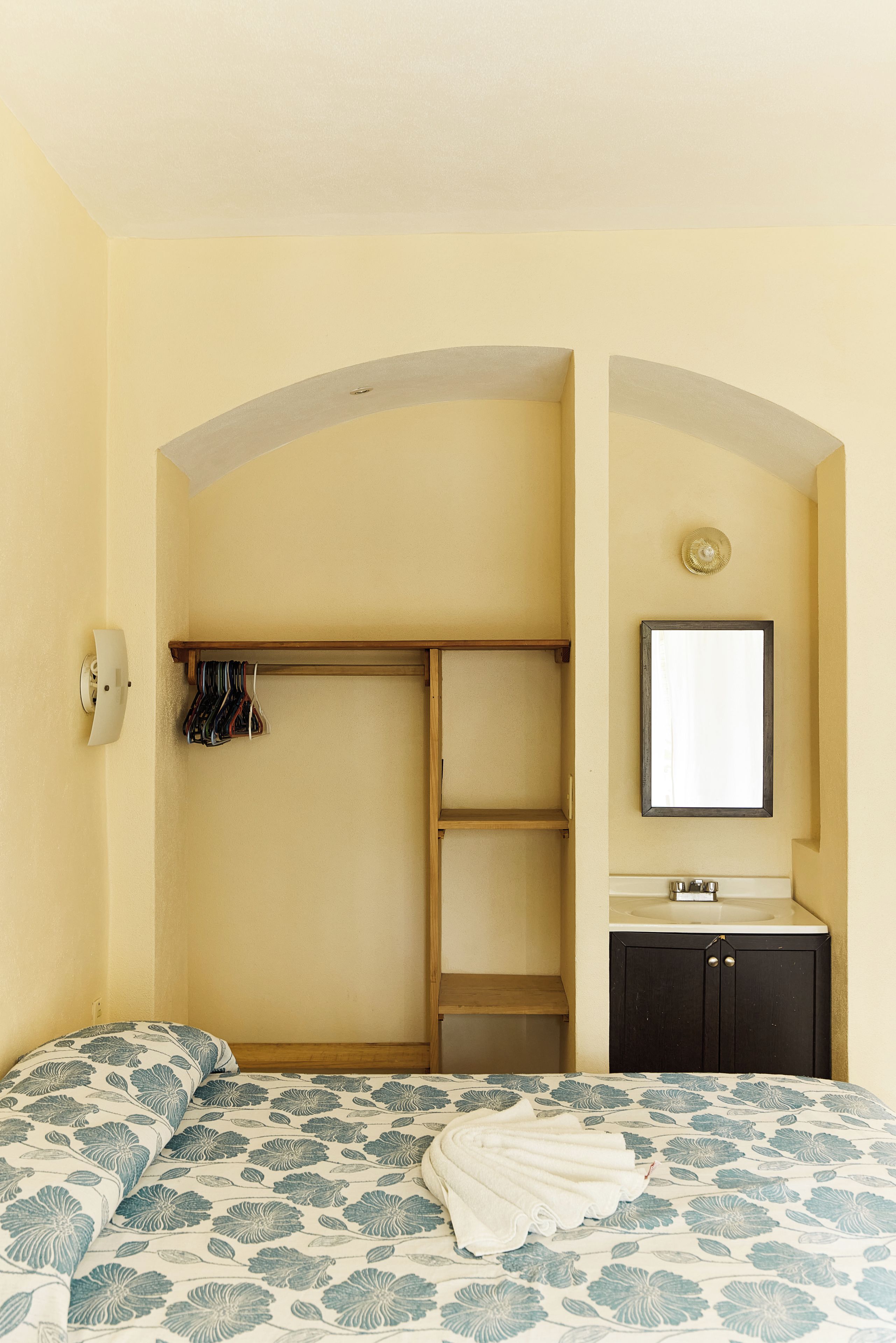 Un dormitorio con cama, armario, espejo y lavabo.