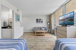 Un salon moderne avec un canapé, une table basse et un téléviseur diffusant une vue sur la ville.