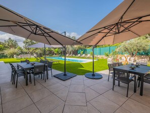 Een terras buiten met een zwembad, omringd door ligstoelen en parasols.
