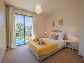 A hotel room with a bed, two bedside lamps, a small table, and a view of a swimming pool. - Spacious property with 2 villas and swimming pool – Grimaud (GRIMAUD)