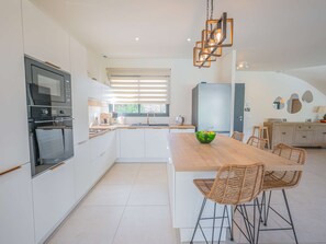 A modern kitchen with a central island, stainless steel appliances, and a dining area with wicker chairs. - Spacious property with 2 villas and swimming pool – Grimaud (GRIMAUD)