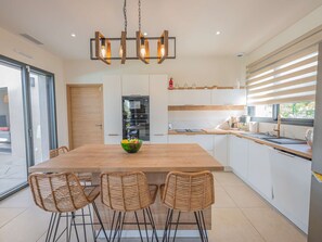 Een moderne keuken met een houten kookeiland, barstoelen en een hanglamp.