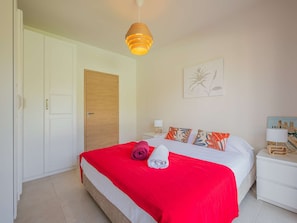 A hotel room with a bed, a wooden door, a wall-mounted artwork, and a nightstand with a lamp. - Spacious property with 2 villas and swimming pool – Grimaud (GRIMAUD)