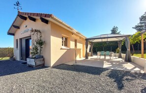 A building with a covered outdoor seating area and a gravel driveway. - Charmant gîte au calme (La Douze)