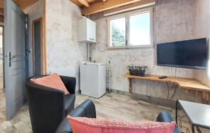A compact living space with a kitchenette, a seating area with a sofa and a table, and a TV mounted on the wall. - Charmant gîte au calme (La Douze)