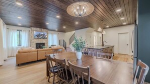 A spacious living area with a wooden dining table, a sofa, and a kitchen island. - Arctic Fox - Yellowstone Getaway! (Island Park)