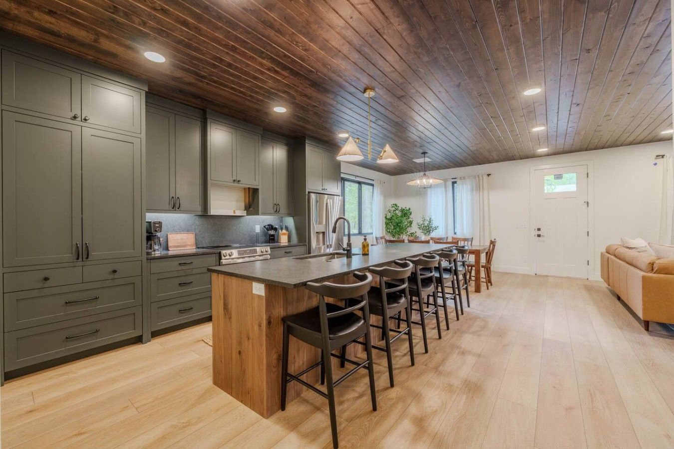 A modern kitchen with a central island, bar stools, and a dining area with a table and chairs.