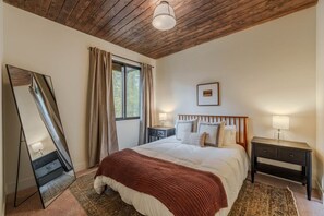 Ein Schlafzimmer mit einem Bett, Nachttischen, einem Spiegel und einem Fenster mit Vorhängen.