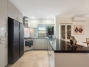 Een moderne keuken met roestvrijstalen apparatuur, een groot eiland en uitzicht op het exterieur.