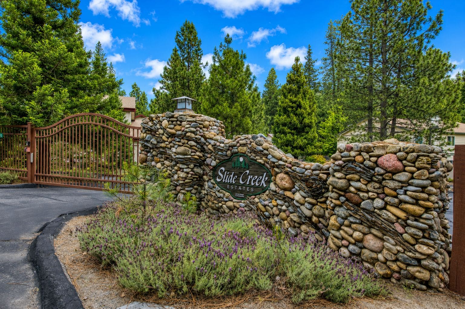 Un mur de pierre sur lequel est apposée une plaque indiquant « Slide Creek Estates », et une entrée fermée par un portail.