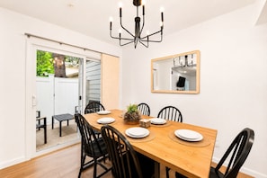 A dining area with a wooden table, black chairs, and a chandelier.