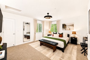 A bedroom with a large bed, bedside tables, a mirror, and a window with curtains.