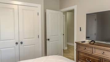 Une chambre à coucher comprenant un lit, une commode, un téléviseur et deux portes fermées.