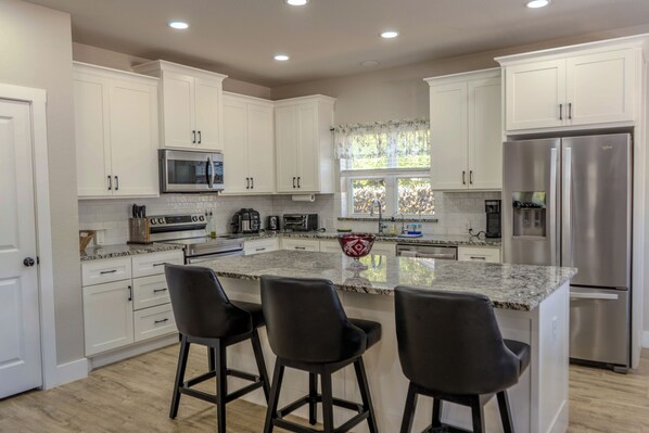 A modern kitchen with white cabinets, stainless steel appliances, and a large island with bar stools.
