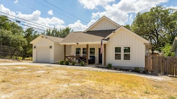 Une maison de plain-pied avec un garage, une véranda et un jardin devant.