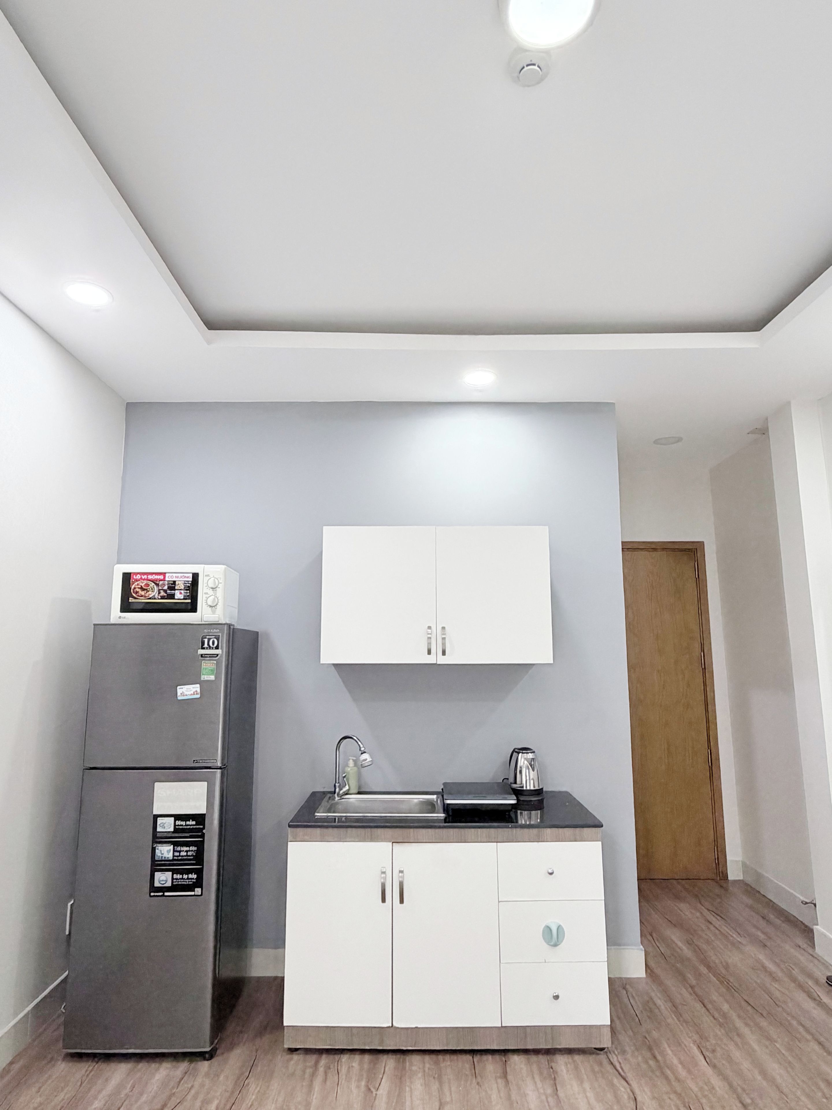 Una cocina compacta con refrigerador integrado, microondas, lavamanos y un mueble con encimera.