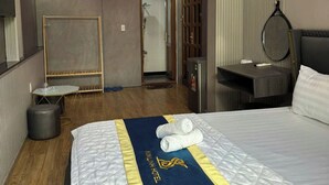 A hotel room with a bed, bedside table, mirror, and a view of the bathroom. - Cherysh House TTT (Ben Thanh)