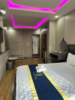 A hotel room with a bed, bedside table, mirror, and a view of the bathroom. - Cherysh House TTT (Ben Thanh)