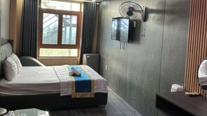 A modern hotel room with a bed, a desk, a fan, and a TV mounted on the wall. - Cherysh House TTT (Ben Thanh)
