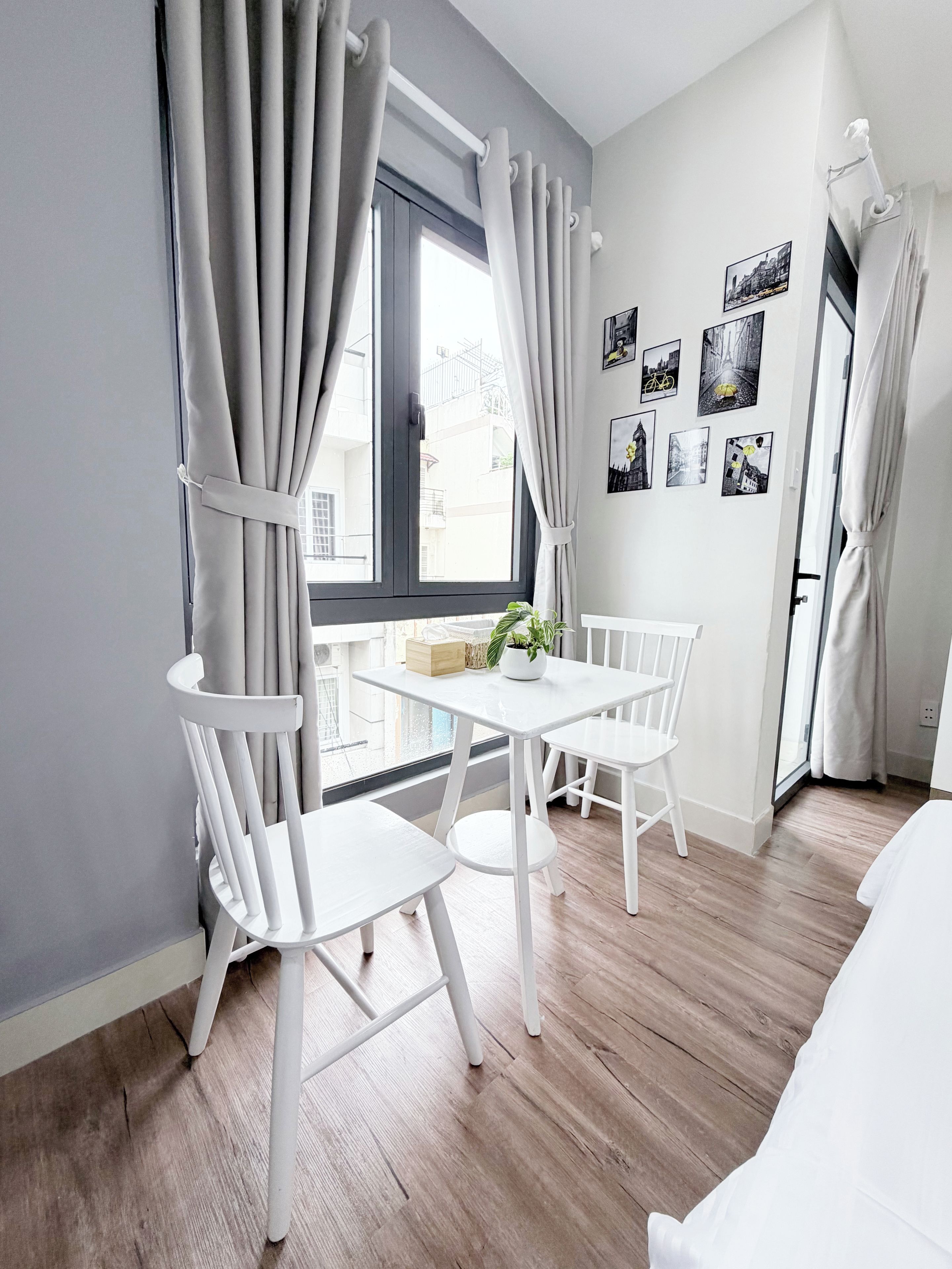 Una habitación moderna con una mesa de comedor y sillas, una ventana con cortinas y una pared decorada con fotografías blanco y negro.