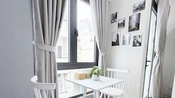 Een moderne kamer met een eettafel en stoelen, een raam met gordijnen, en een wand versierd met zwart-wit foto's.