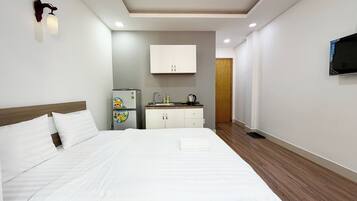 Ein Hotelzimmer mit Bett, einer Küchenzeile, einem an der Wand montierten Fernseher und Holzboden.