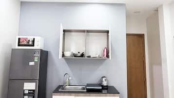 Una piccola cucina accessoriata con frigorifero, forno a microonde, lavello e pensili.