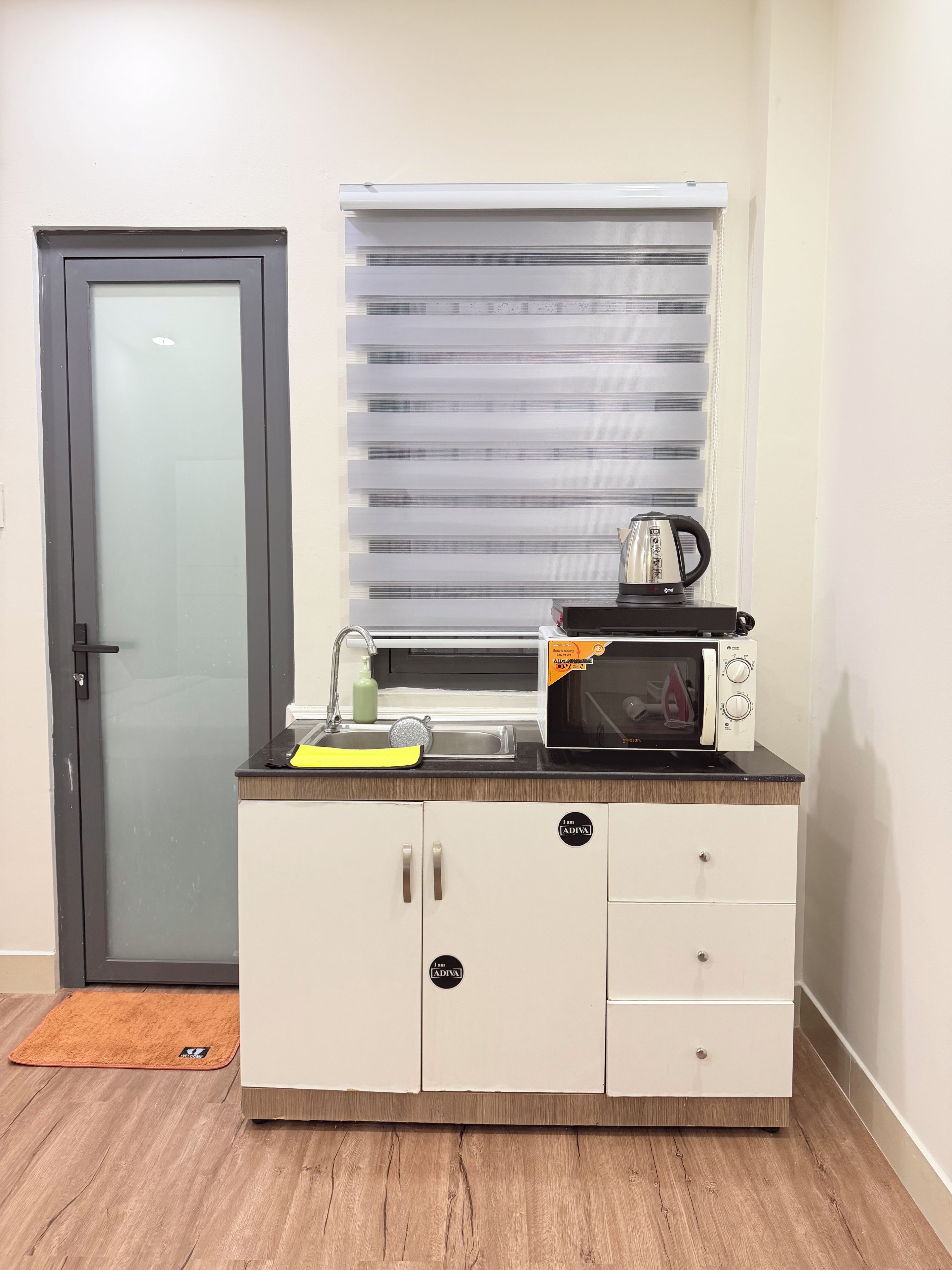 Una kitchenette equipada con microondas, tetera y lavabo.