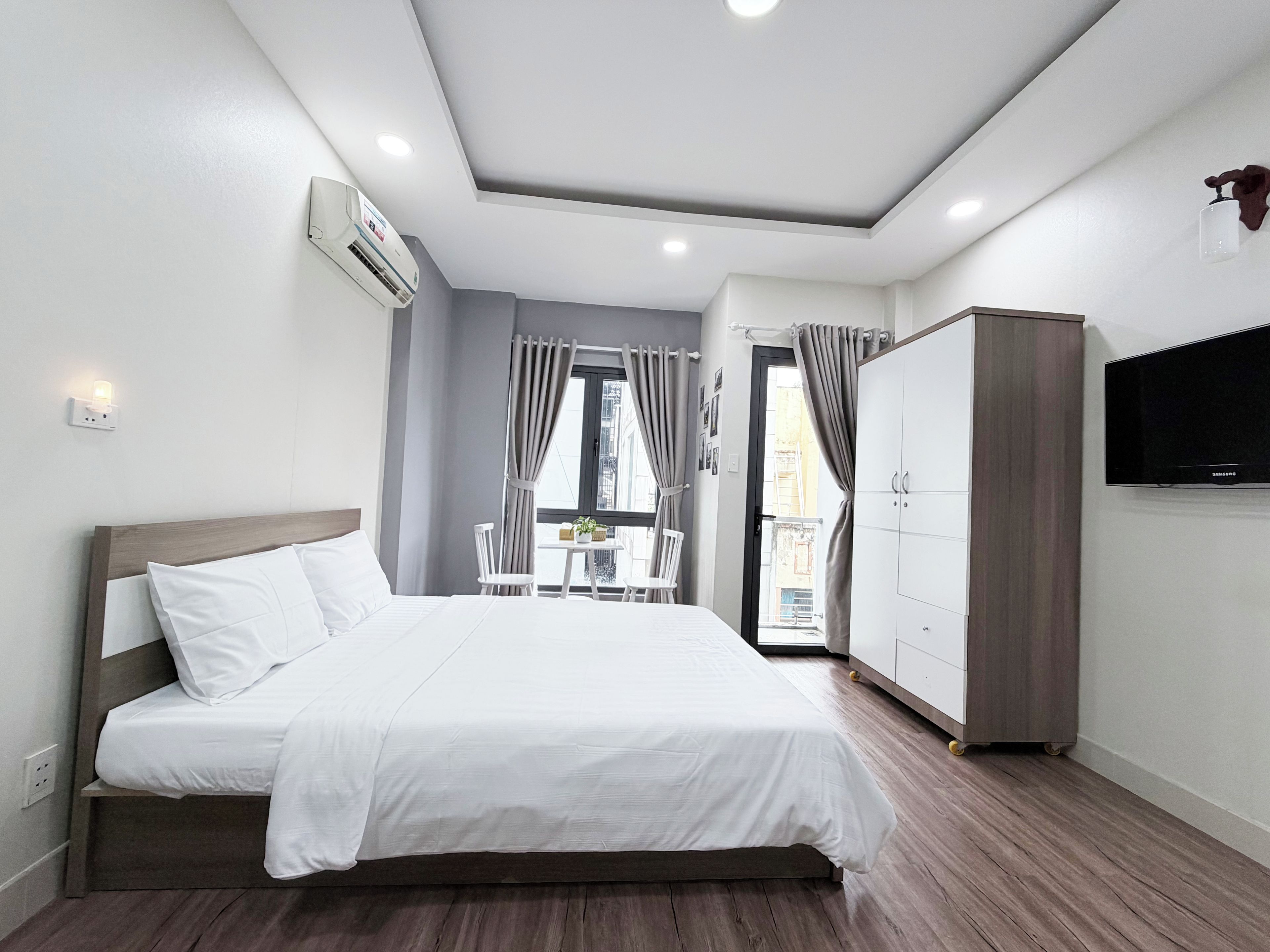 Una habitación de hotel con cama, armario, televisor y balcón con mesa y sillas.