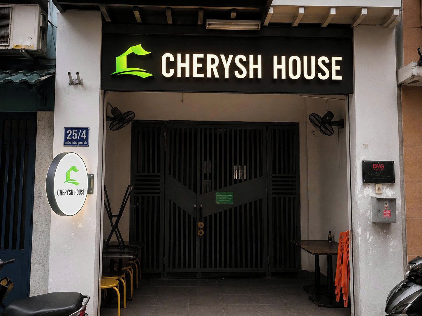 La entrada a Cherysh House, un edificio con fachada blanco y negro, un letrero con logotipo verde y el número '25/4' indicando su dirección.