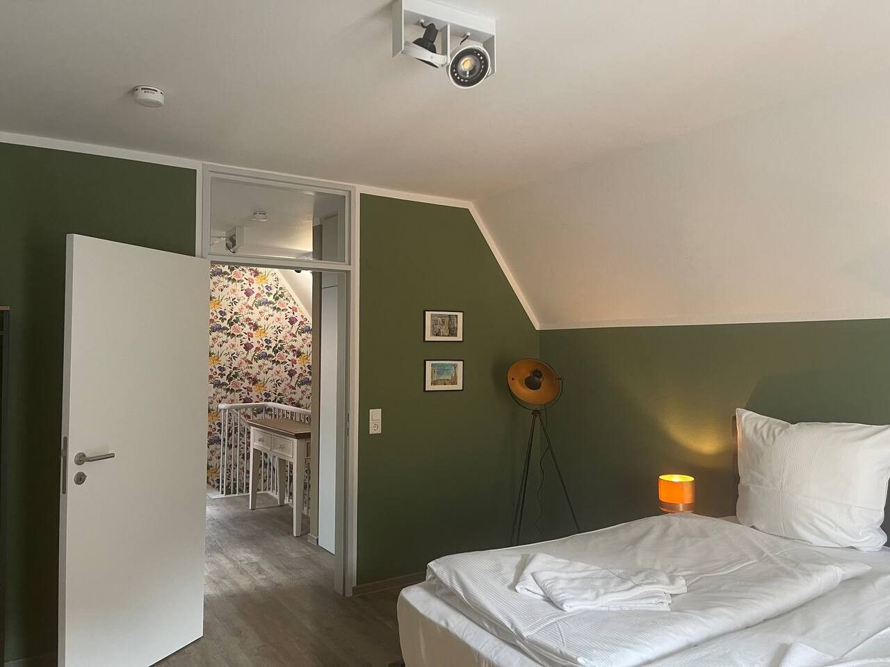 A bedroom with a bed, a desk, and a chair in a corner.