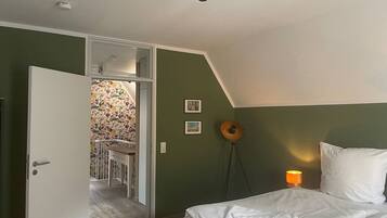 A bedroom with a bed, a desk, and a chair in a corner.
