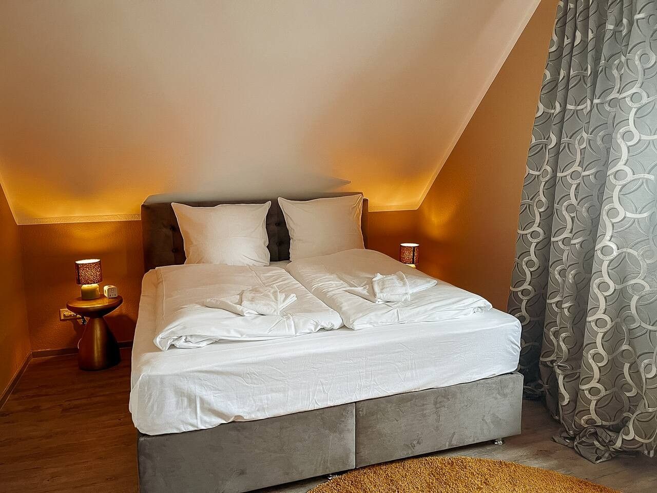 A bedroom with a bed, bedside tables, and curtains.